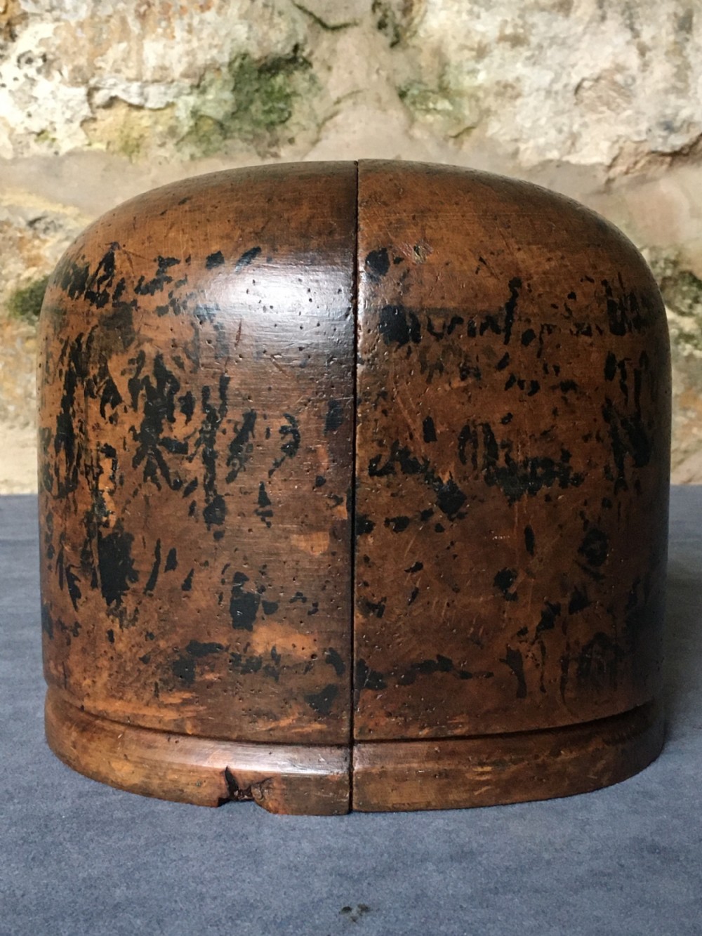 A two-piece carved wooden milliners hat block featuring a rounded dome top and a weathered brown and black painted finish. View XV