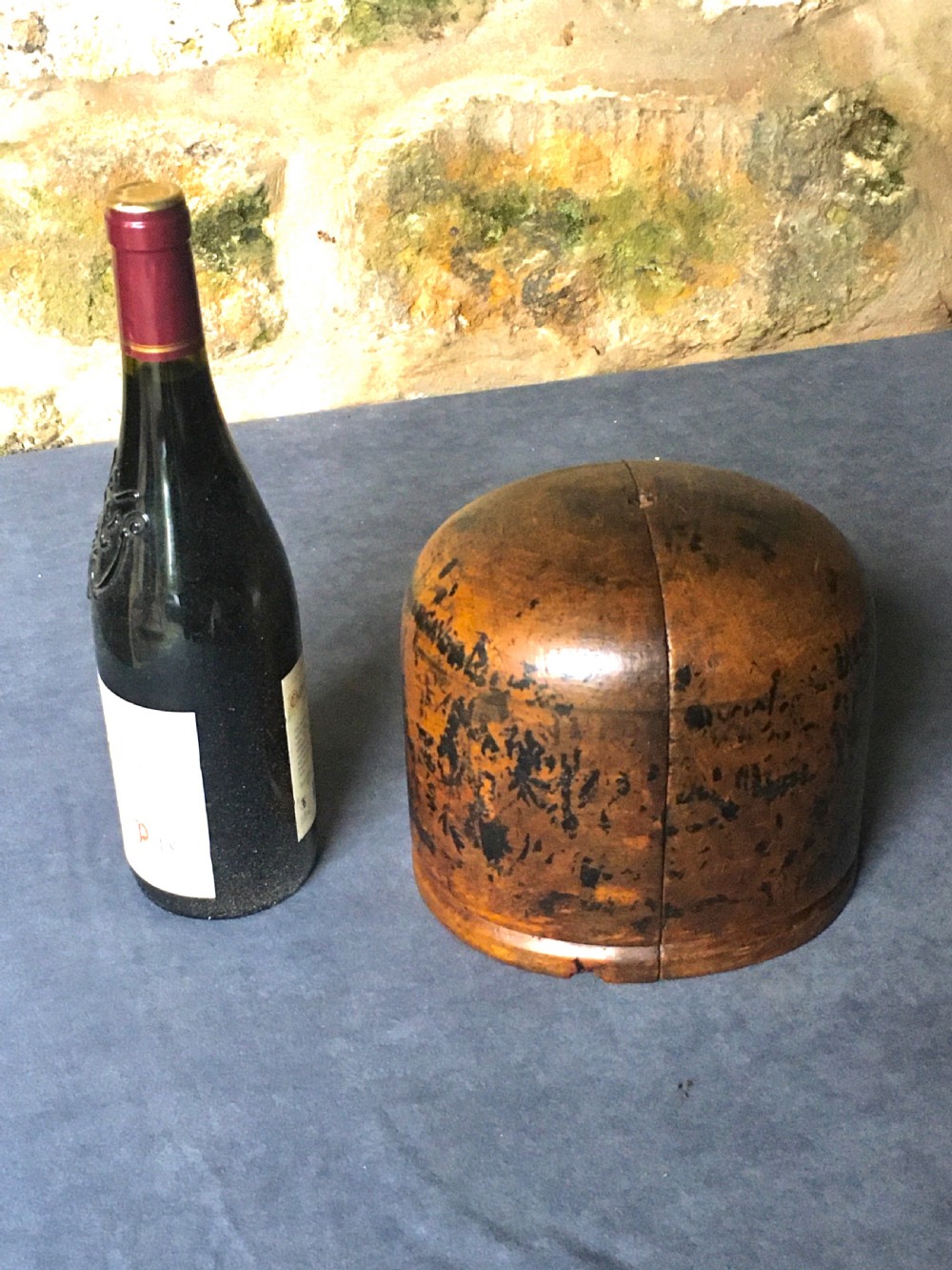 A two-piece carved wooden milliners hat block featuring a rounded dome top and a weathered brown and black painted finish. View XVI