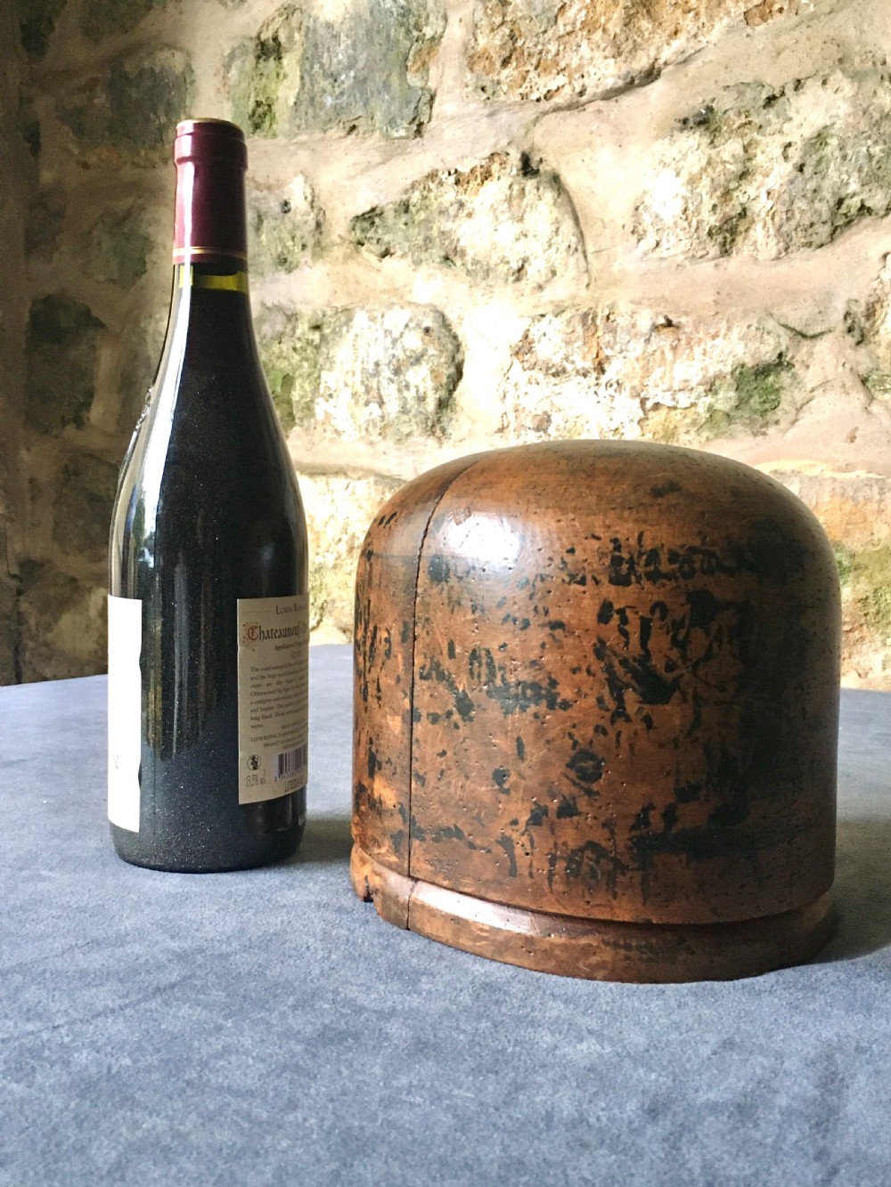 A two-piece carved wooden milliners hat block featuring a rounded dome top and a weathered brown and black painted finish. View XVIII