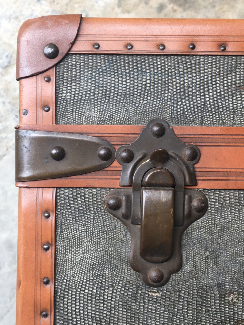 An antique French hard-sided luggage suitcase featuring grey canvas, tan leather trim, brass hardware, and a leather carrying handle. View XXII