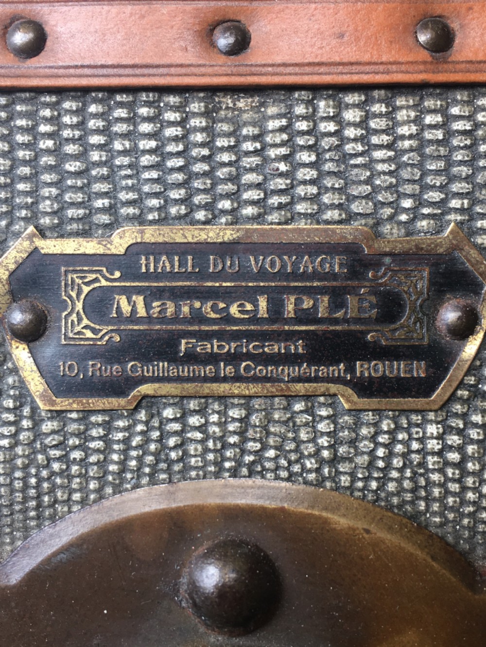 An antique French hard-sided luggage suitcase featuring grey canvas, tan leather trim, brass hardware, and a leather carrying handle. View XXVI