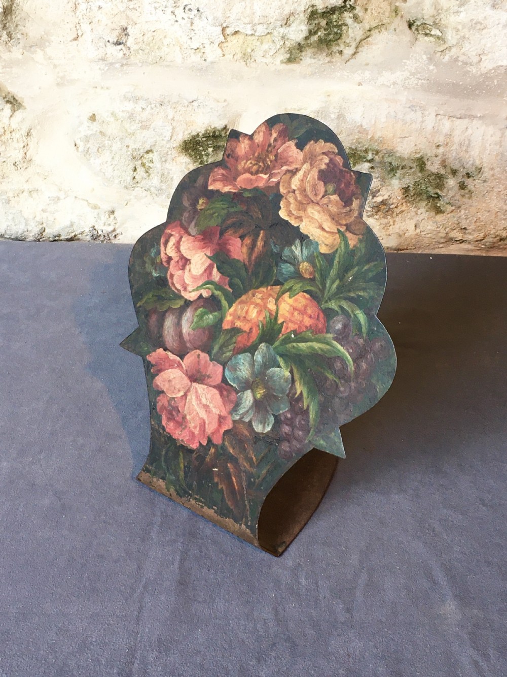 A contoured painted sheet metal stand depicting a botanical floral and fruit still life arrangement.