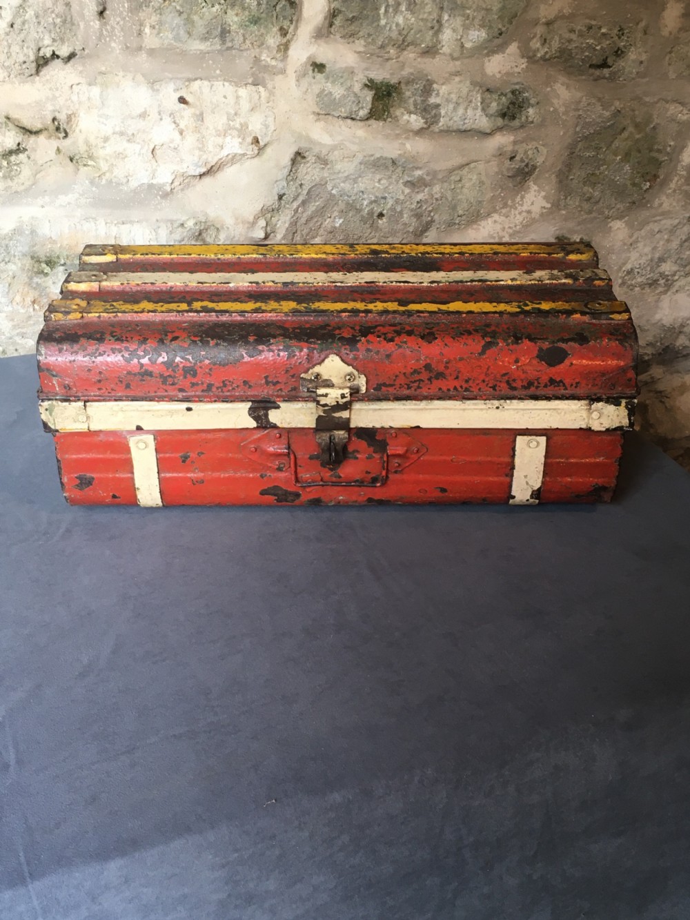 A rectangular early twentieth-century painted sheet metal trunk with ribbed details, metal latches, and distressed red, yellow, cream, and turquoise paintwork. View XIV