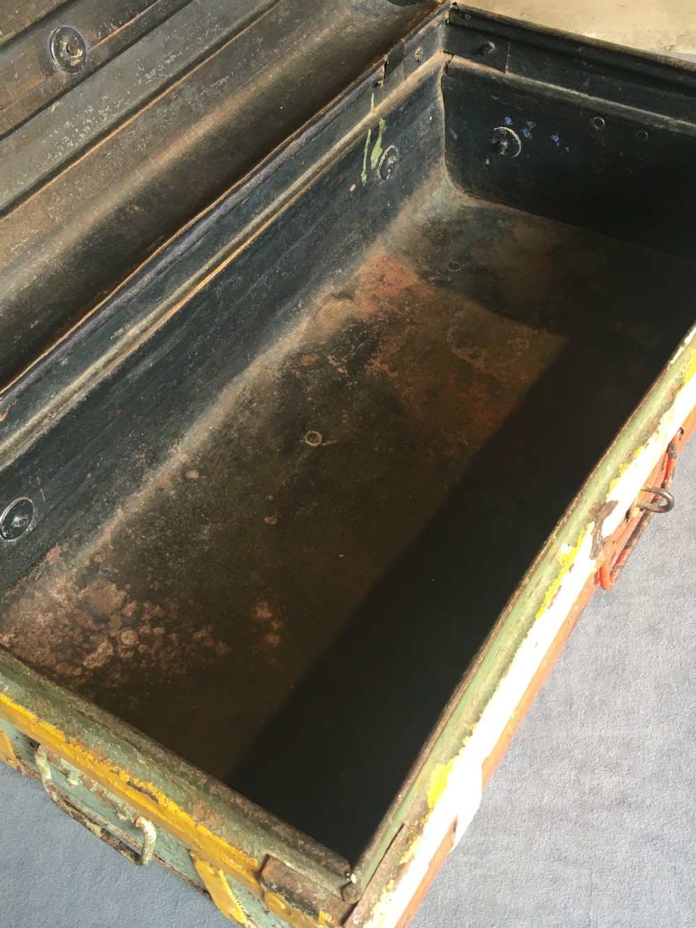 A rectangular early twentieth-century painted sheet metal trunk with ribbed details, metal latches, and distressed red, yellow, cream, and turquoise paintwork. View XIX