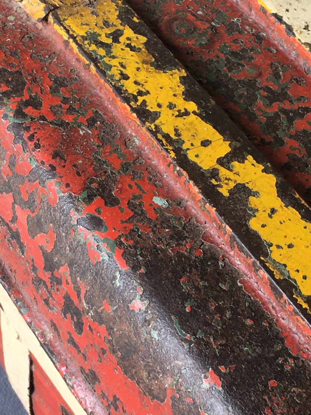 A rectangular early twentieth-century painted sheet metal trunk with ribbed details, metal latches, and distressed red, yellow, cream, and turquoise paintwork. View XXIII
