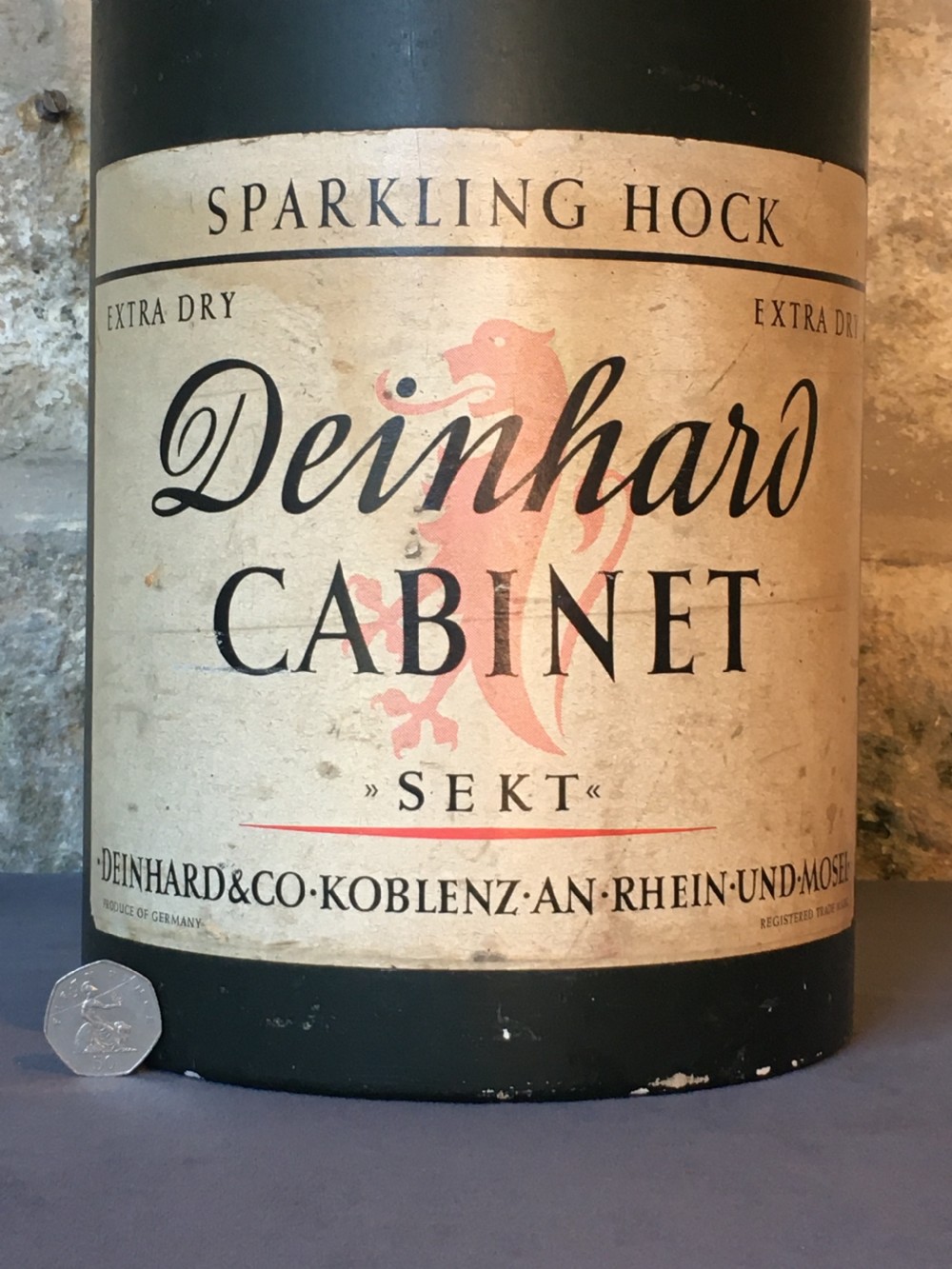 A group of four large vintage dark green glass advertising wine and champagne bottles featuring original paper labels. View V