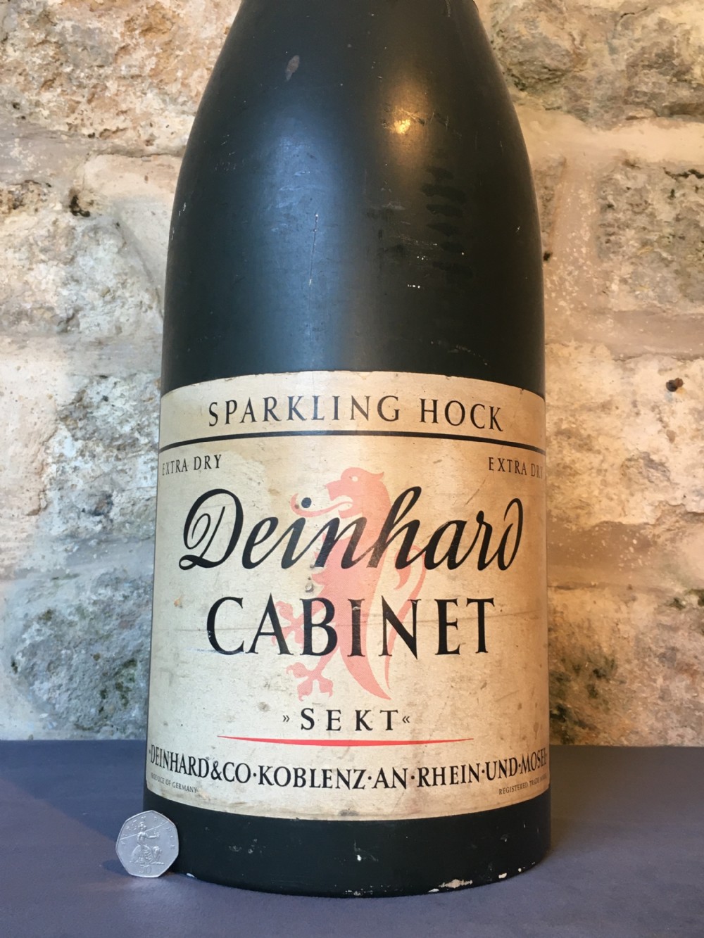 A group of four large vintage dark green glass advertising wine and champagne bottles featuring original paper labels. View VI