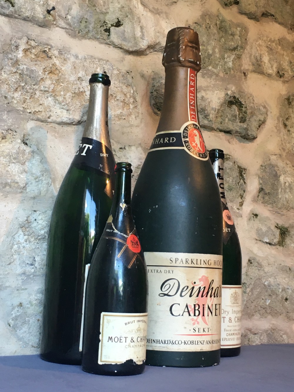 A group of four large vintage dark green glass advertising wine and champagne bottles featuring original paper labels. View VIII
