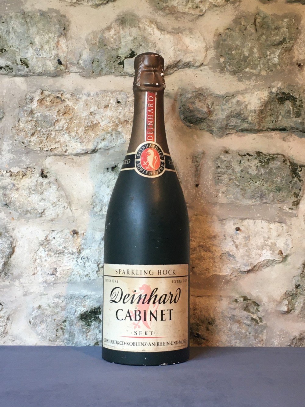 A group of four large vintage dark green glass advertising wine and champagne bottles featuring original paper labels. View X