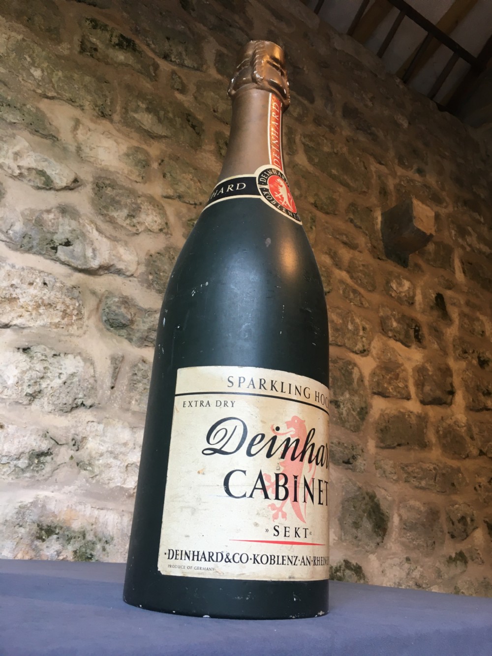 A group of four large vintage dark green glass advertising wine and champagne bottles featuring original paper labels. View XII