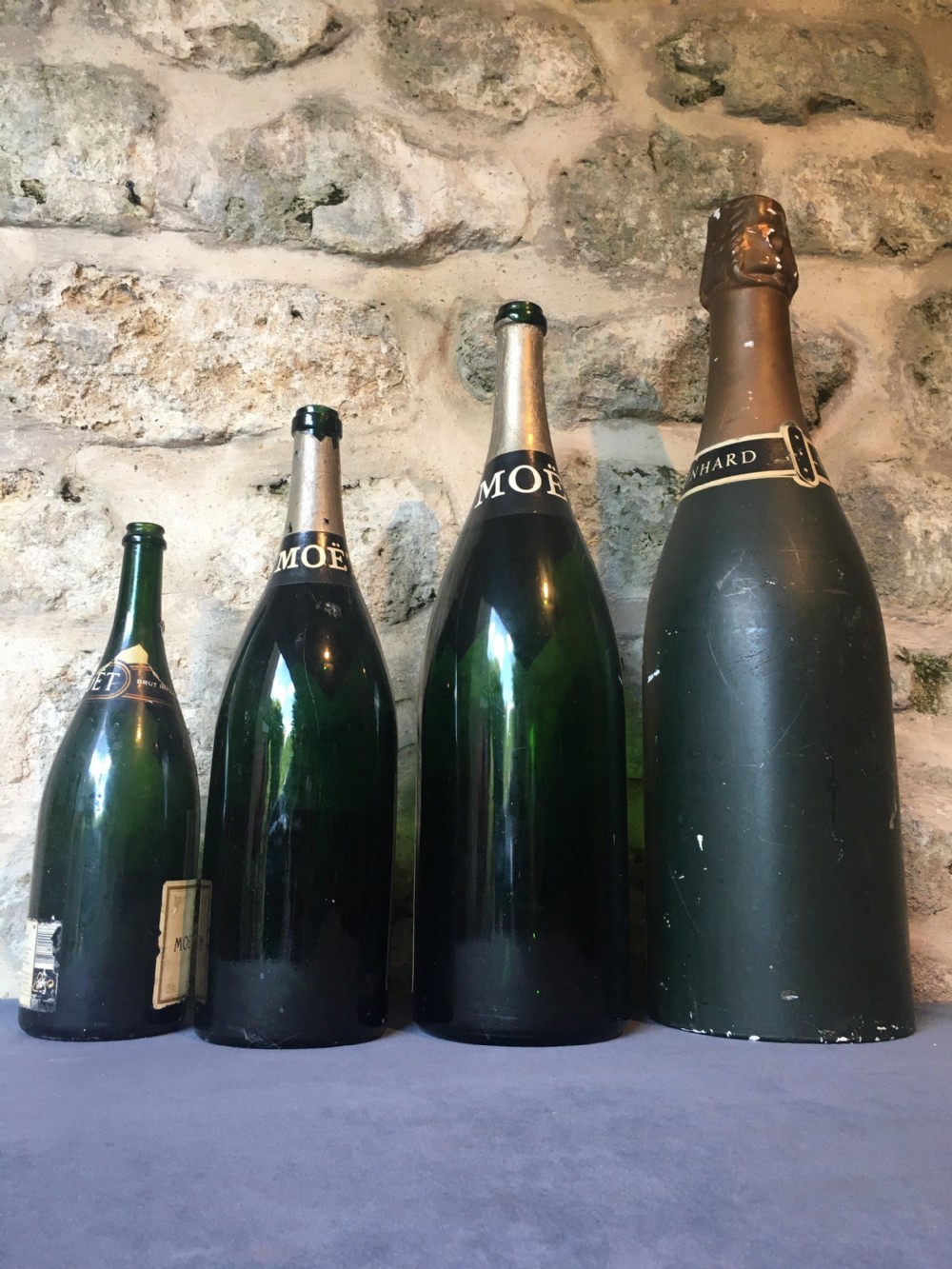 A group of four large vintage dark green glass advertising wine and champagne bottles featuring original paper labels. View XIII