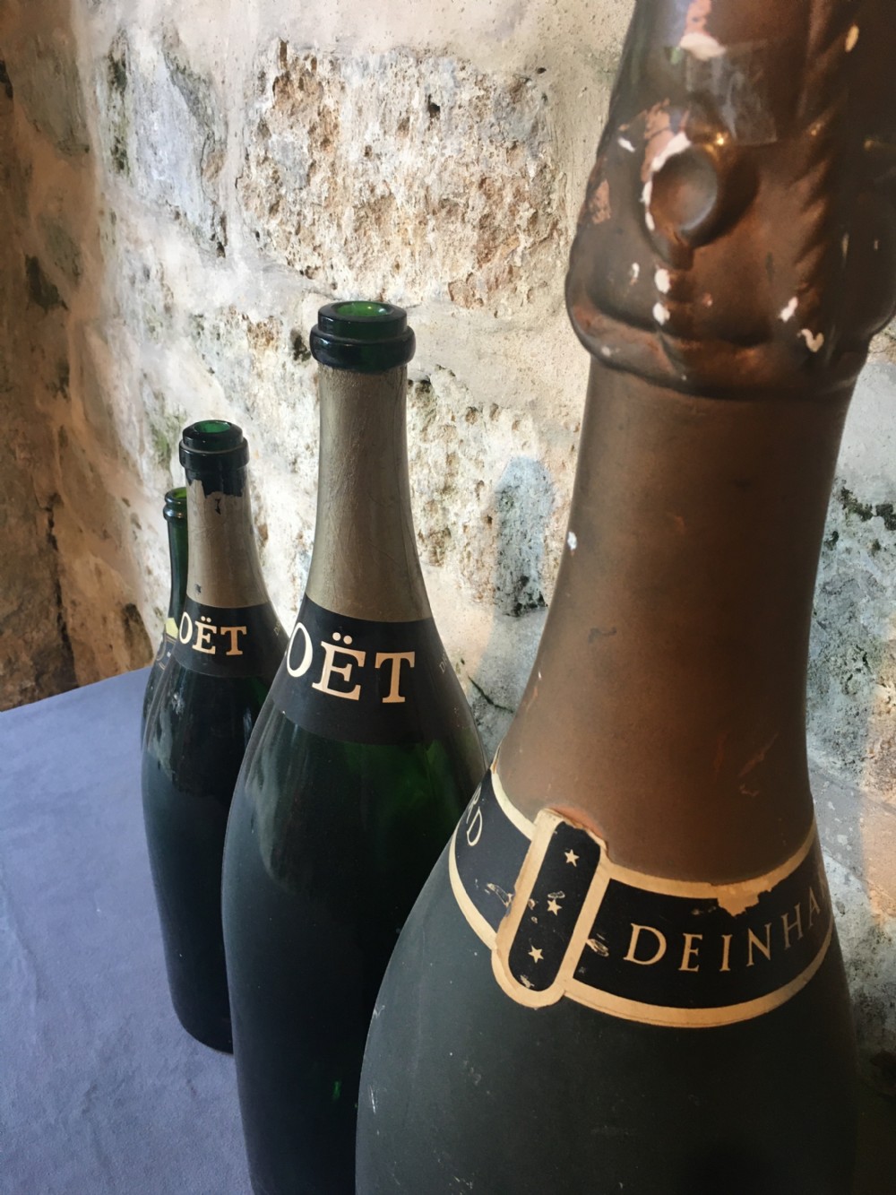 A group of four large vintage dark green glass advertising wine and champagne bottles featuring original paper labels. View XIV