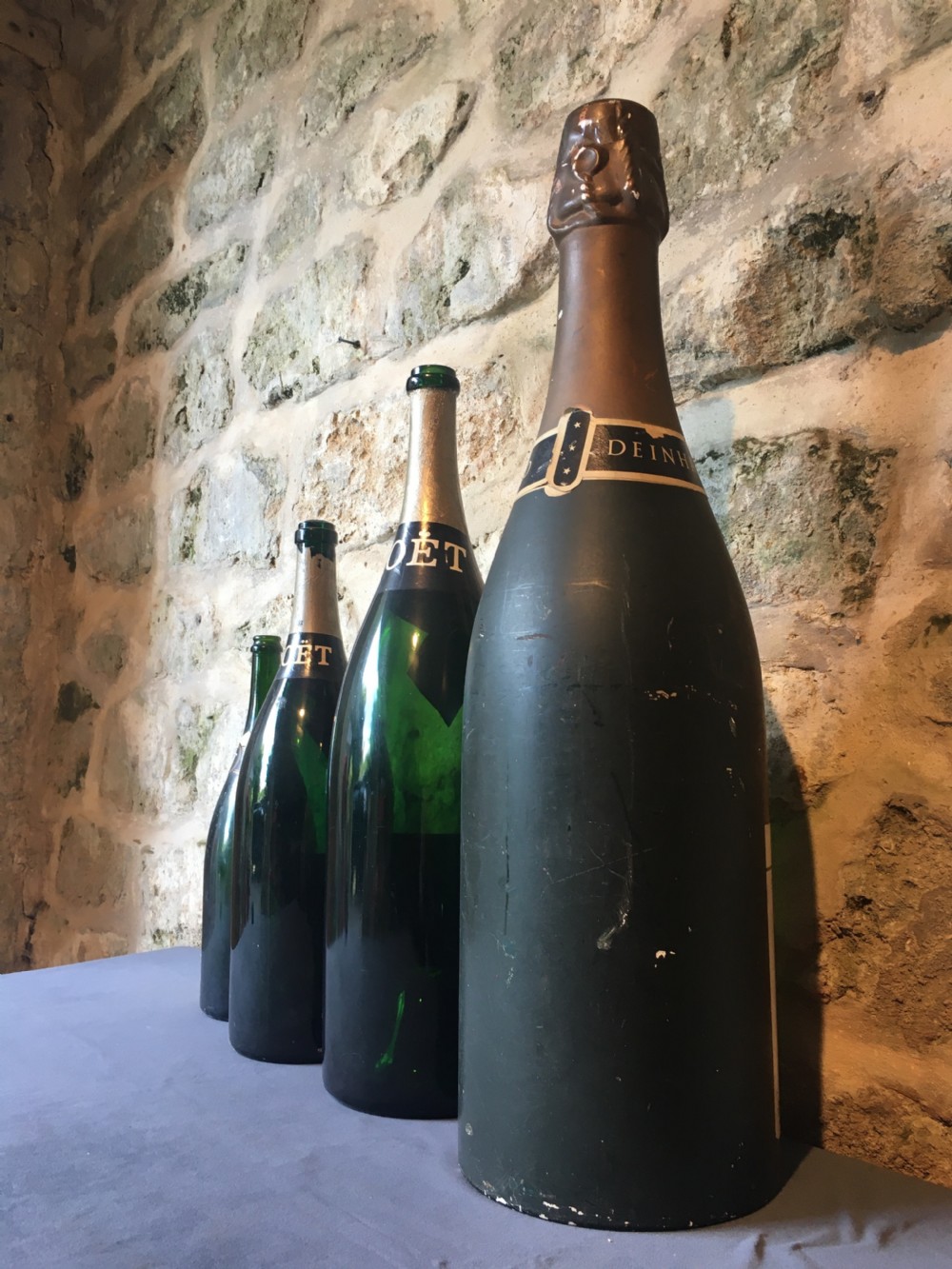 A group of four large vintage dark green glass advertising wine and champagne bottles featuring original paper labels. View XV