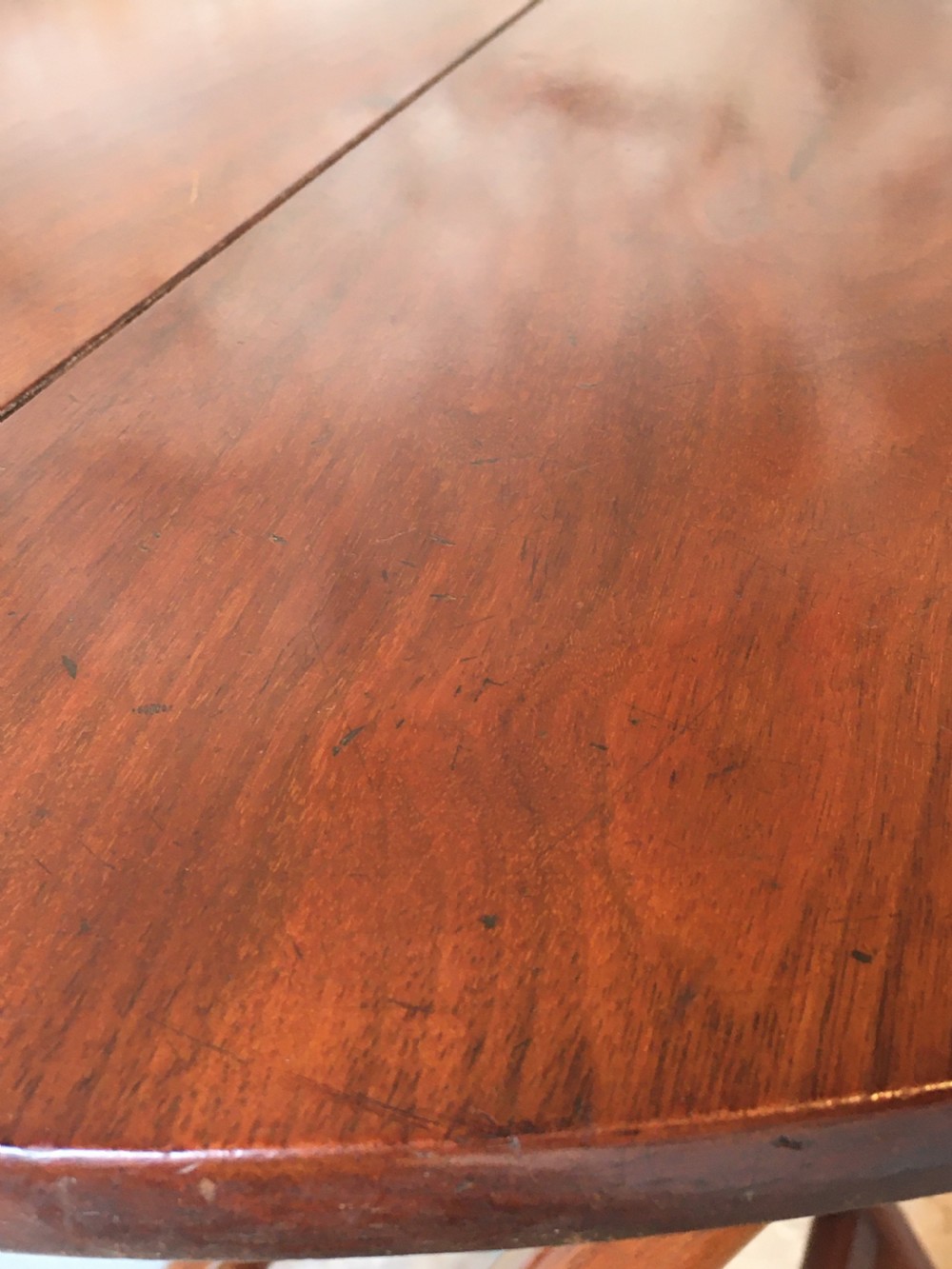 A Victorian mahogany folding occasional table with a hinged circular top supported by curved X-frame legs. View X