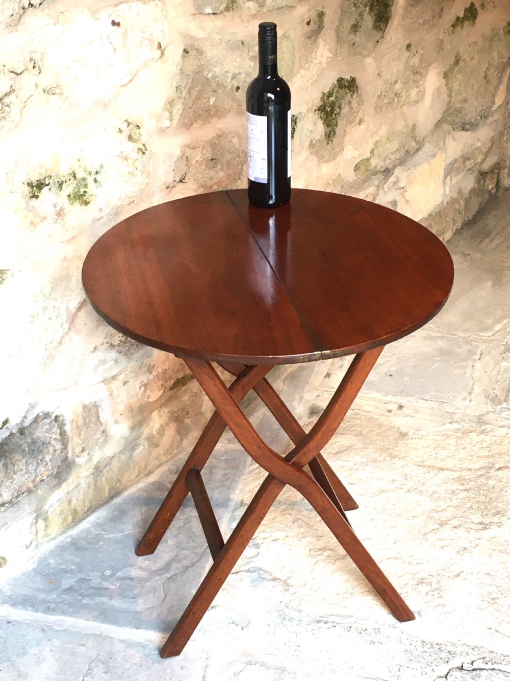 A Victorian mahogany folding occasional table with a hinged circular top supported by curved X-frame legs. View XVI