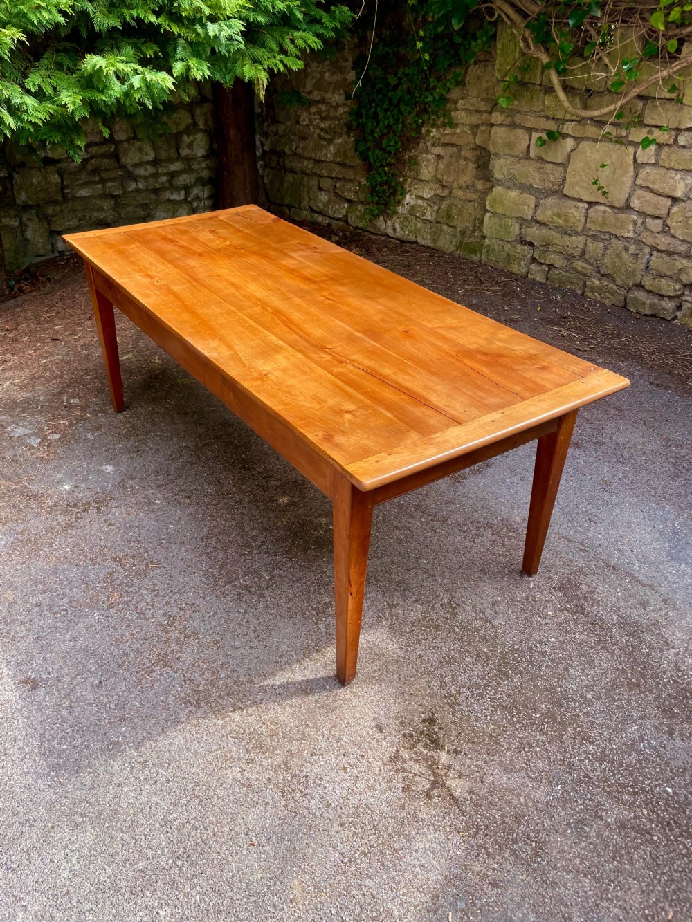 A rectangular wooden refectory dining table with a plank top, breadboard ends, and four tapered legs.