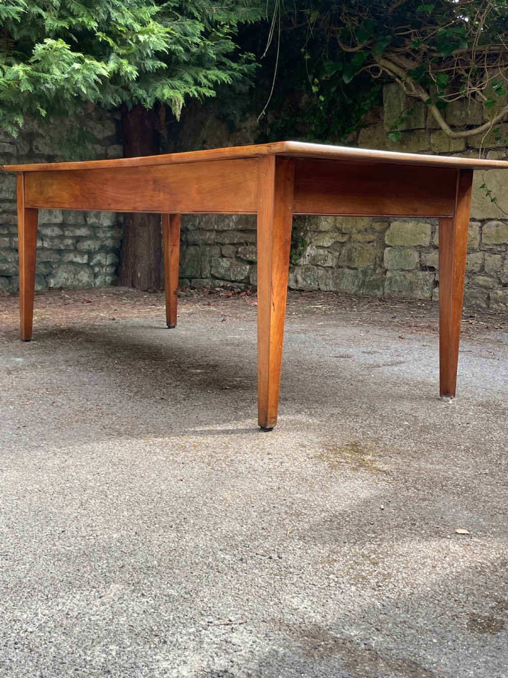 A rectangular wooden refectory dining table with a plank top, breadboard ends, and four tapered legs. View V