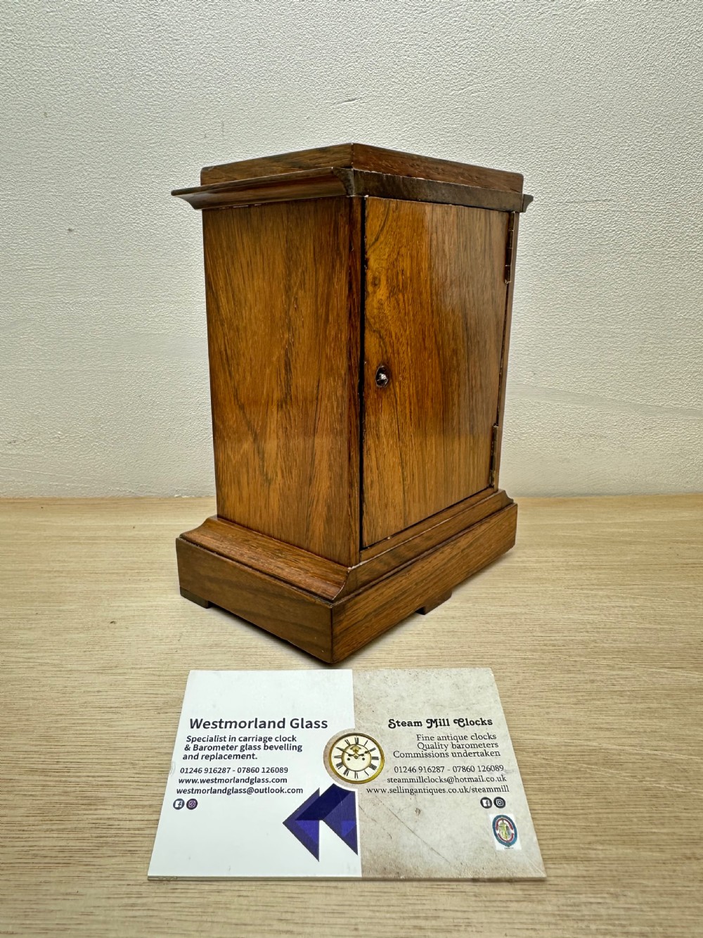A rectangular dark rosewood mantel clock featuring an enamel dial with Roman numerals surrounded by decorative brass spandrels. View II