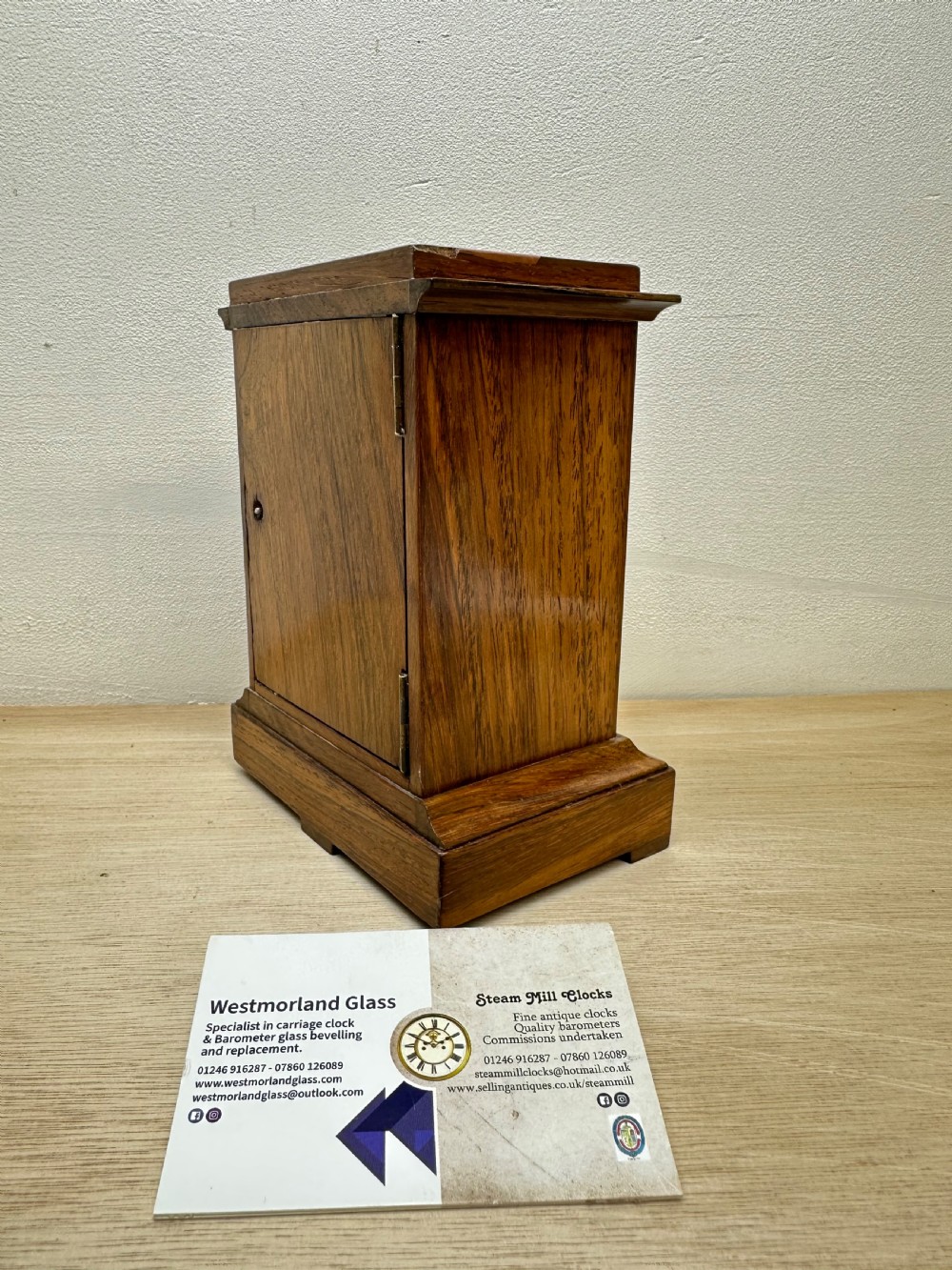 A rectangular dark rosewood mantel clock featuring an enamel dial with Roman numerals surrounded by decorative brass spandrels. View III