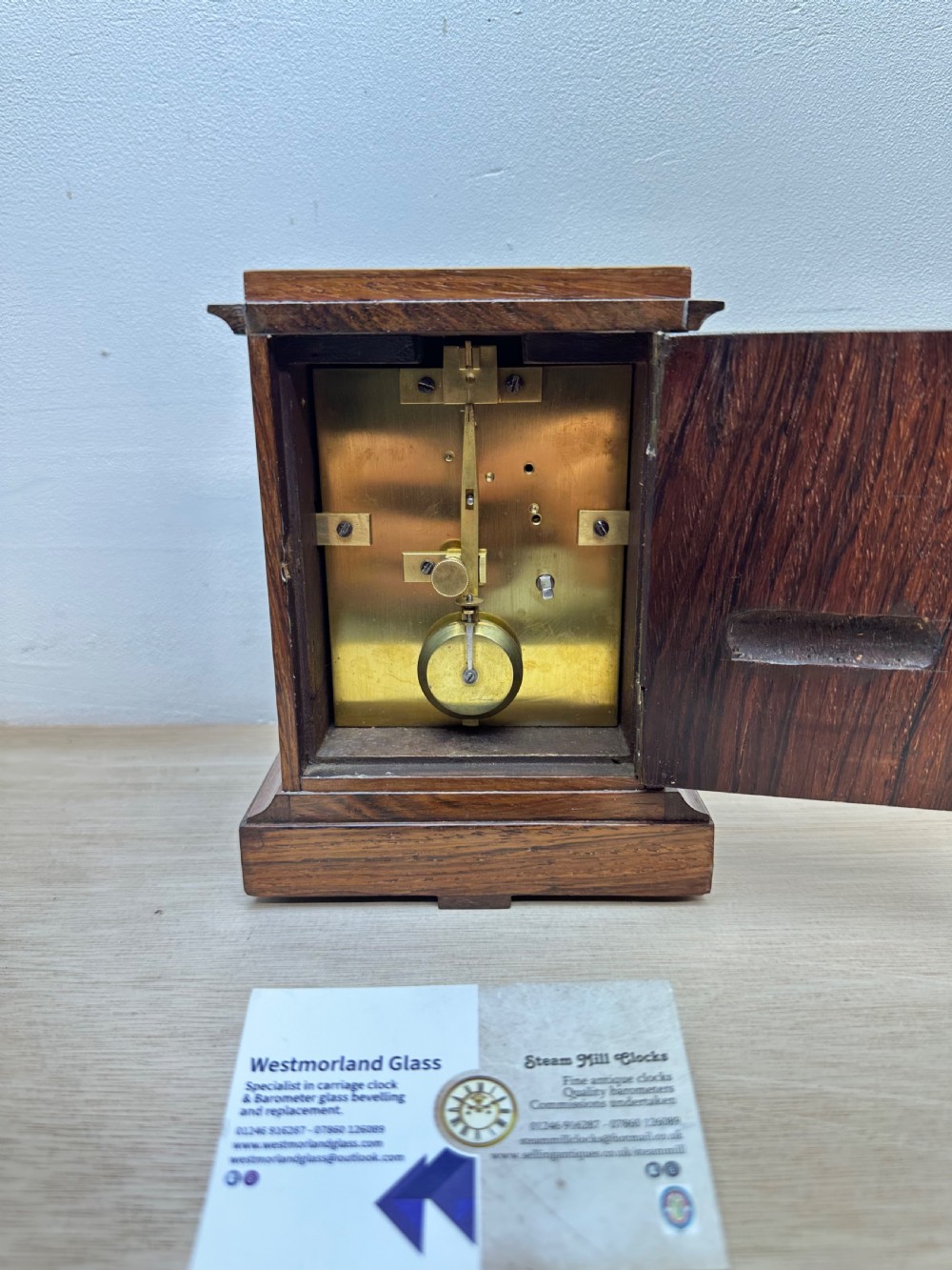 A rectangular dark rosewood mantel clock featuring an enamel dial with Roman numerals surrounded by decorative brass spandrels. View IV
