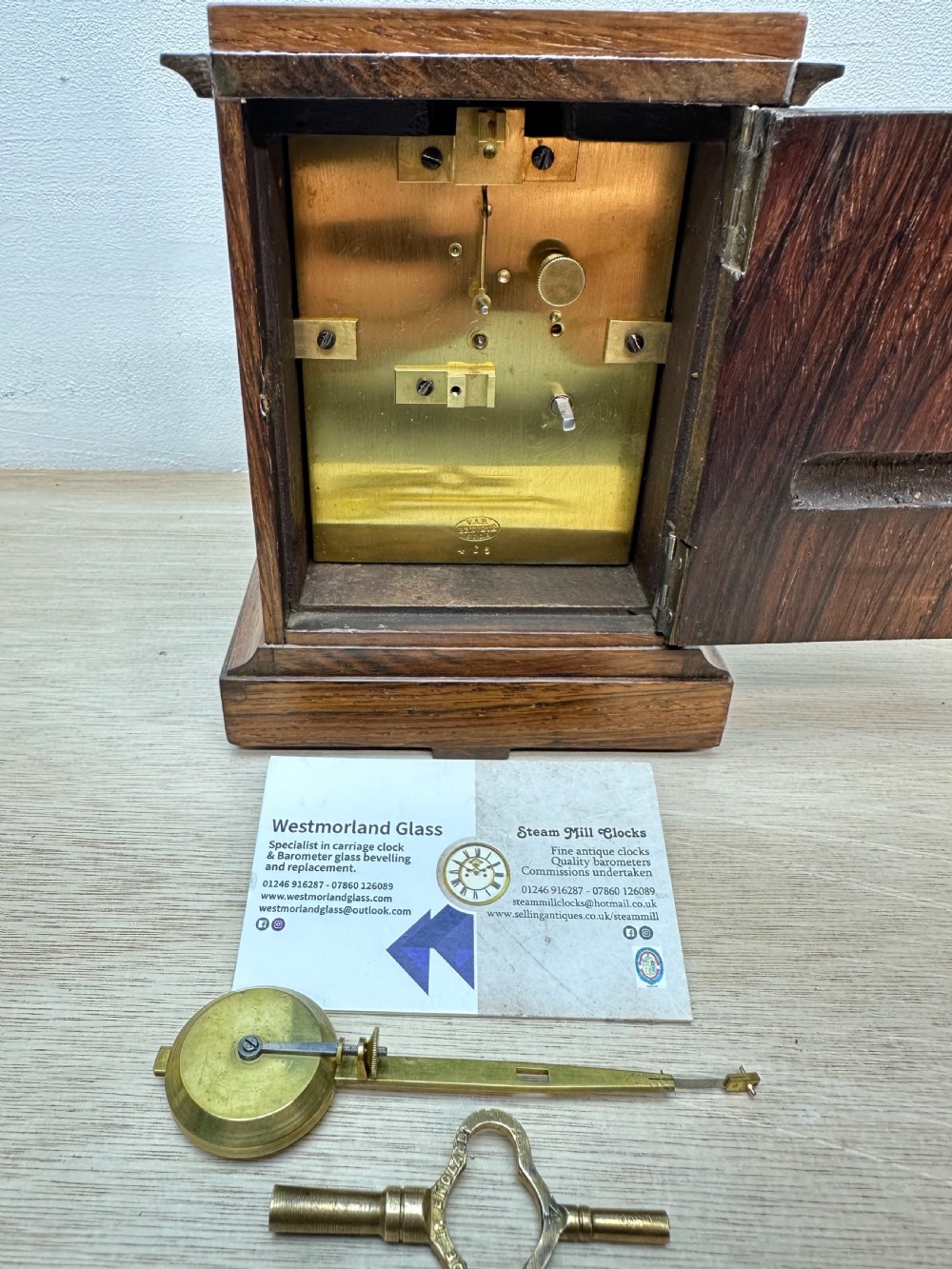 A rectangular dark rosewood mantel clock featuring an enamel dial with Roman numerals surrounded by decorative brass spandrels. View X