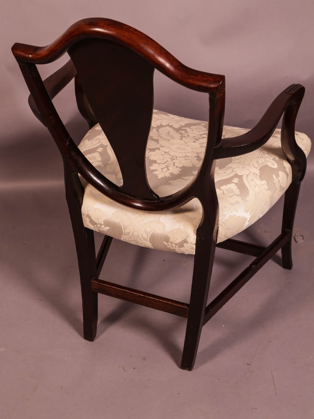 A dark mahogany Hepplewhite period carver armchair featuring a carved open backrest, curved arms, and a cream patterned damask seat. View III