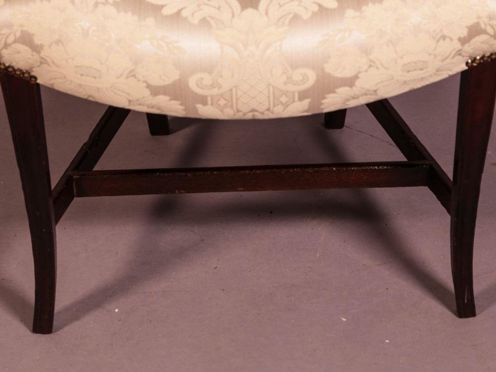 A dark mahogany Hepplewhite period carver armchair featuring a carved open backrest, curved arms, and a cream patterned damask seat. View VI