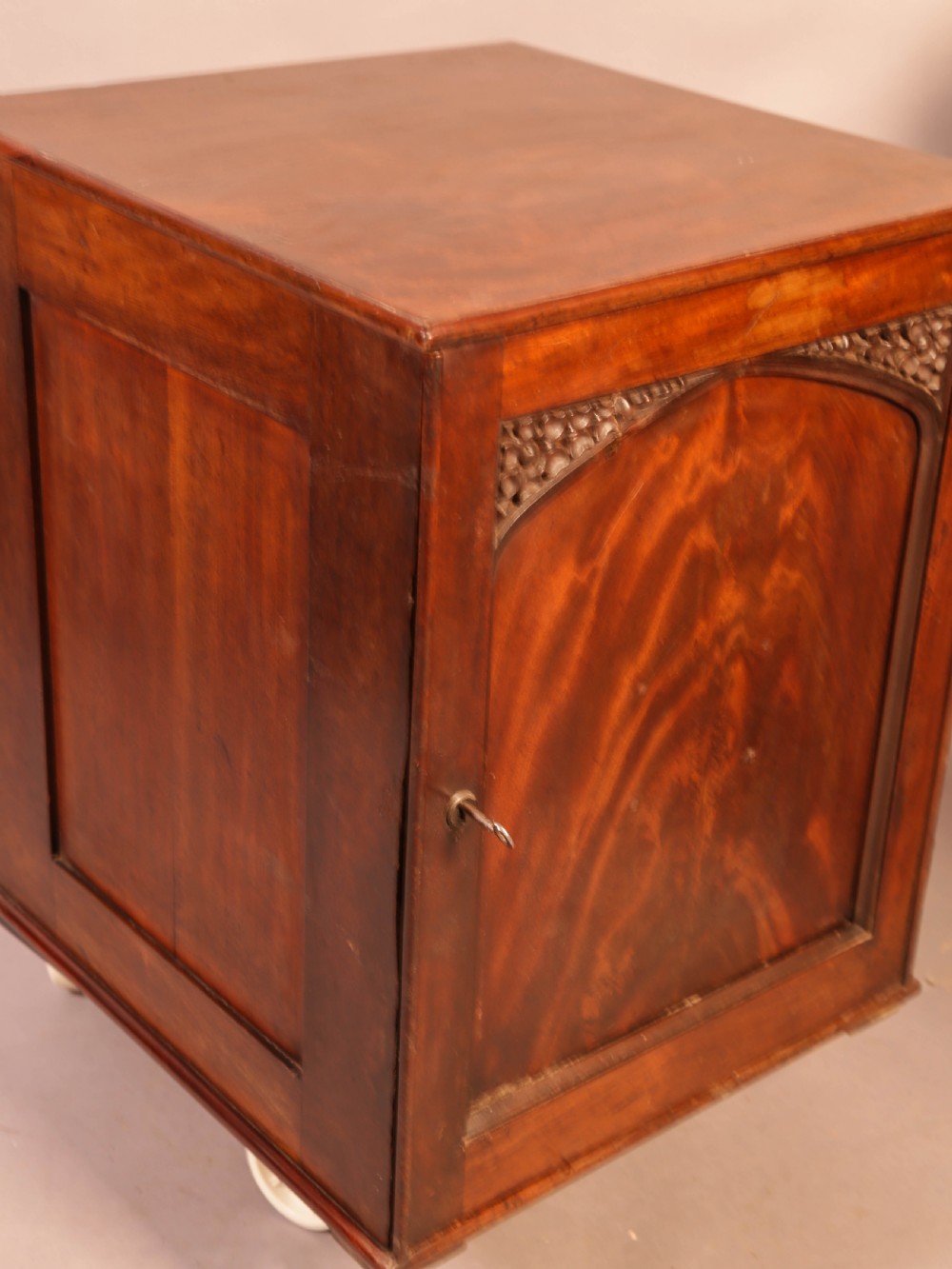 A rich brown mahogany Victorian collectors cabinet with a arched panel door and carved spandrels. View IV