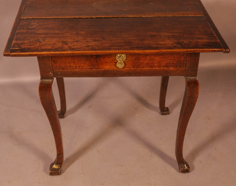 An early 18th-century dark oak side table featuring cabriole legs, a single frieze drawer, and a brass drop handle. View II