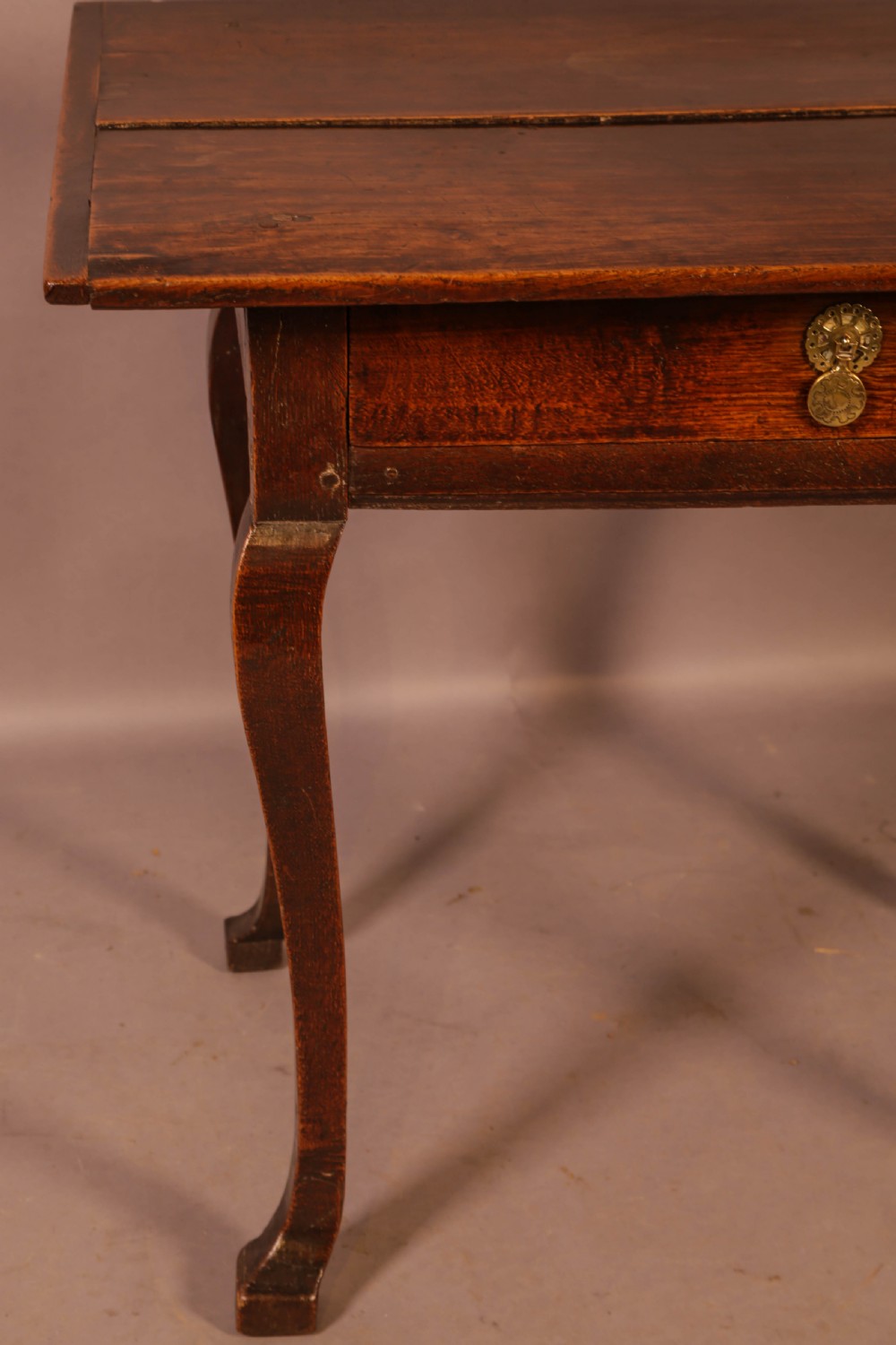 An early 18th-century dark oak side table featuring cabriole legs, a single frieze drawer, and a brass drop handle. View IV