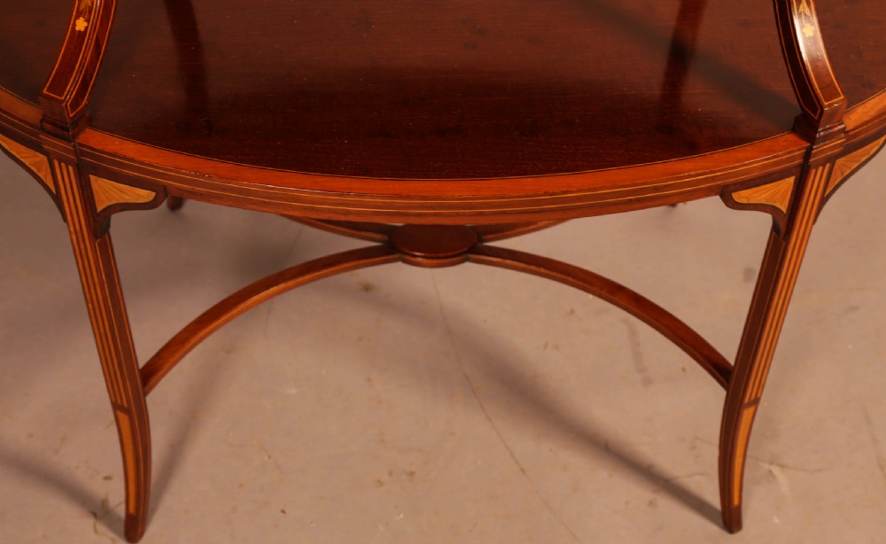 An Edwardian two-tier oval mahogany etagere featuring detailed central floral marquetry inlay, slender curved supports, and swept legs with crossbanding. View VII