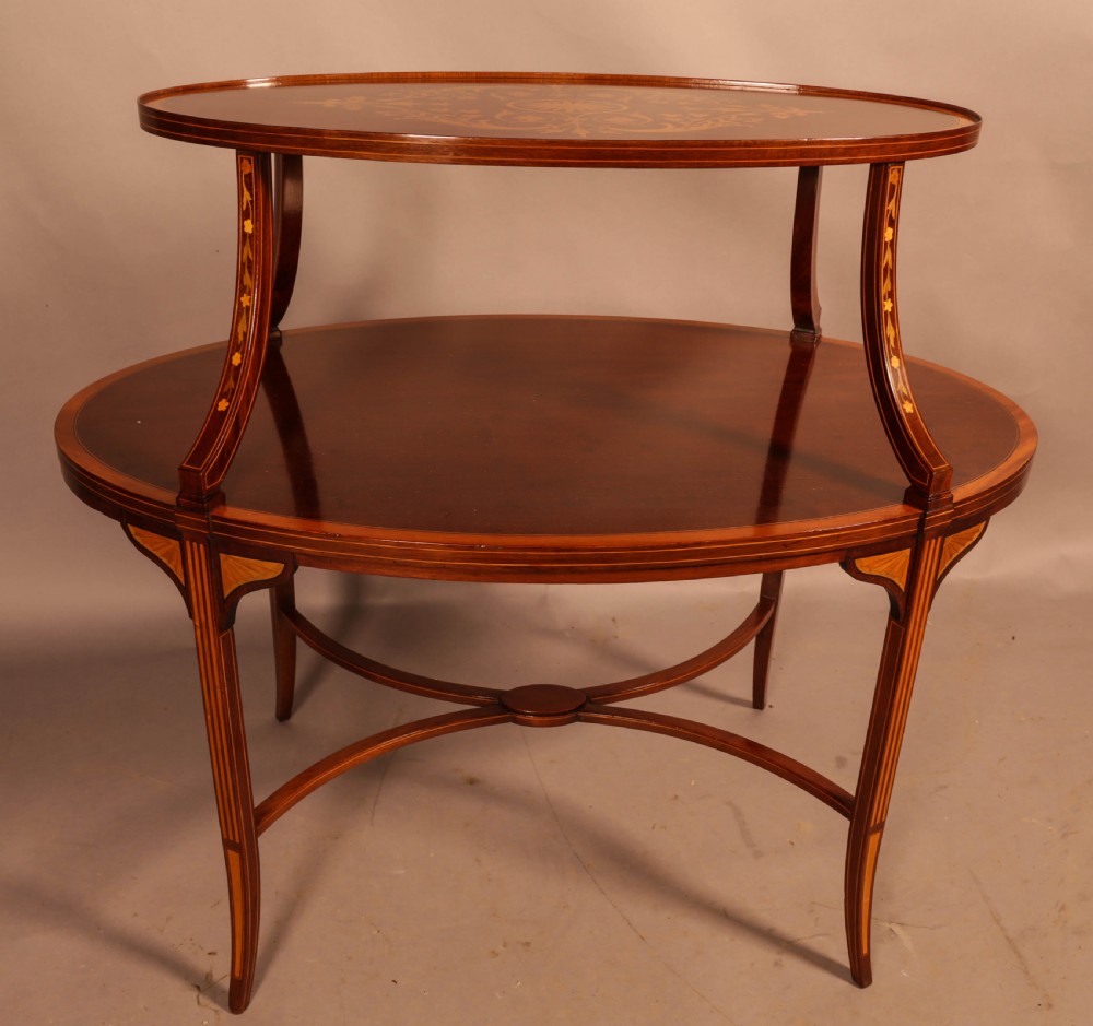 An Edwardian two-tier oval mahogany etagere featuring detailed central floral marquetry inlay, slender curved supports, and swept legs with crossbanding. View IX