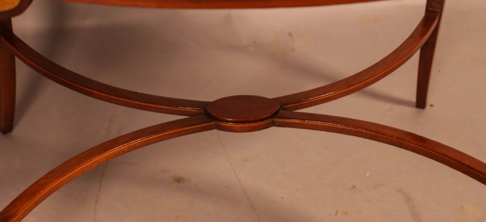 An Edwardian two-tier oval mahogany etagere featuring detailed central floral marquetry inlay, slender curved supports, and swept legs with crossbanding. View XII