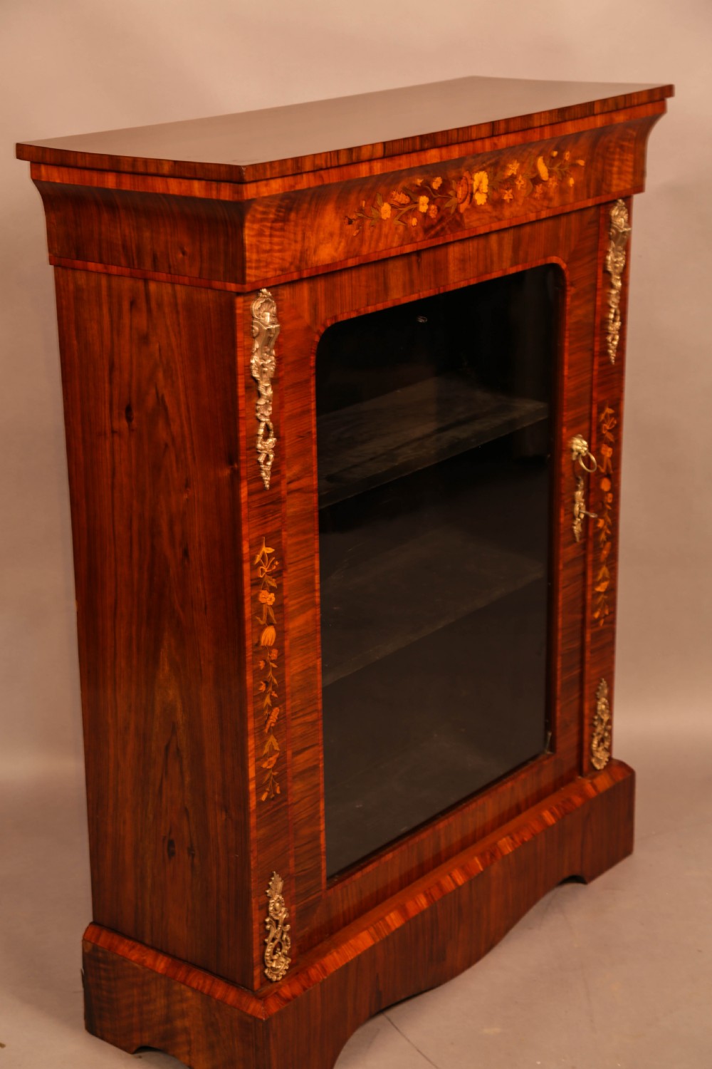 A Victorian figured walnut pier cabinet featuring a single glazed door, floral marquetry inlay, and ornate gilt-metal mounts. View II