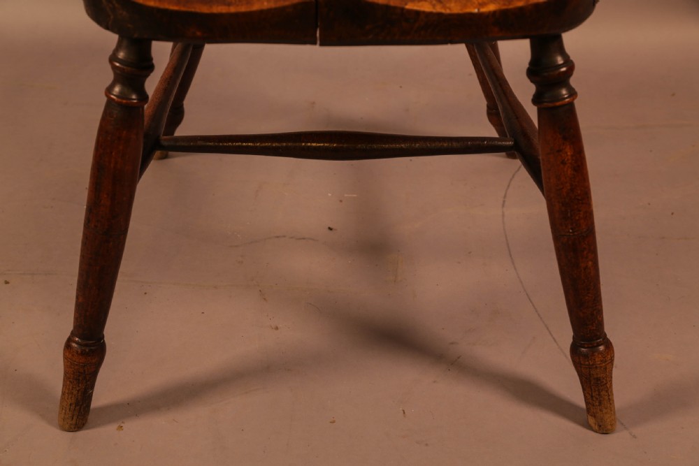 A dark brown antique wooden Windsor armchair featuring vertical spindles, a contoured saddle seat, and hand-carved snake head terminals on the arms and top rail. View XX