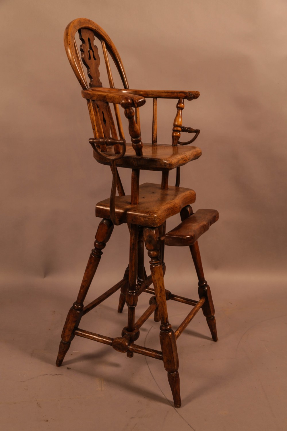 An antique Victorian yew wood child exercise chair featuring a hoop-back top seat, side metal handles, coiled steel springs, and turned legs. View II
