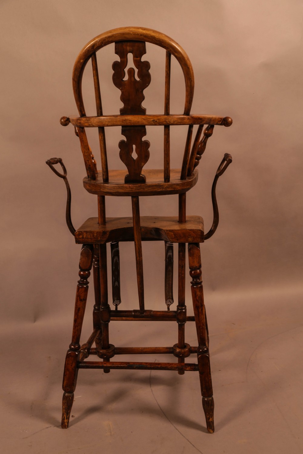 An antique Victorian yew wood child exercise chair featuring a hoop-back top seat, side metal handles, coiled steel springs, and turned legs. View III