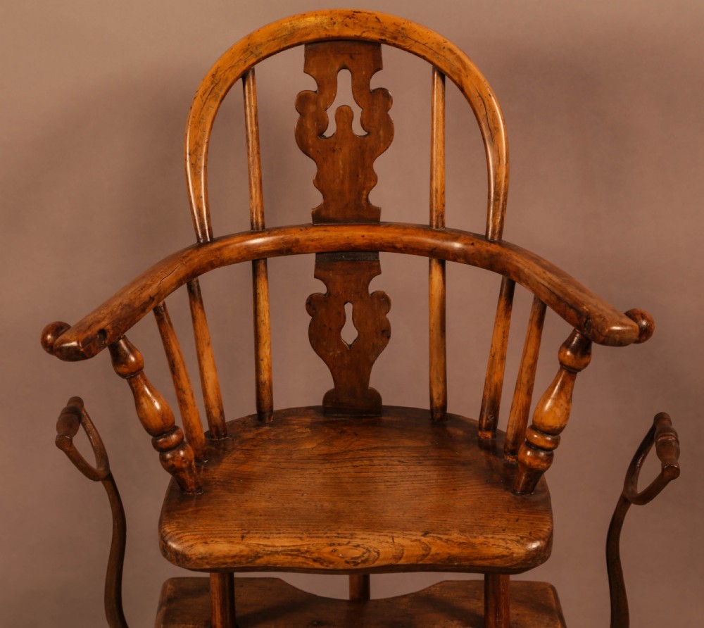 An antique Victorian yew wood child exercise chair featuring a hoop-back top seat, side metal handles, coiled steel springs, and turned legs. View V
