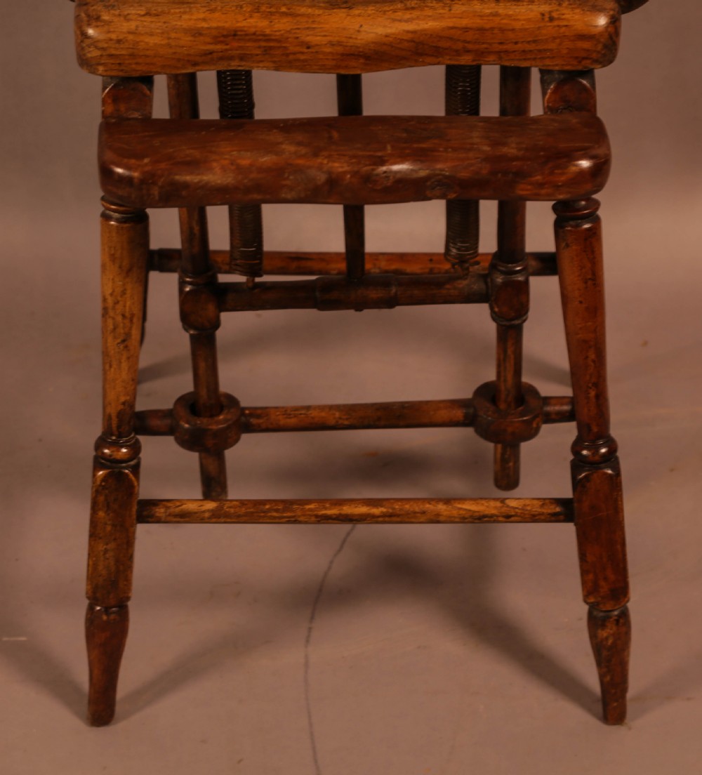 An antique Victorian yew wood child exercise chair featuring a hoop-back top seat, side metal handles, coiled steel springs, and turned legs. View VI