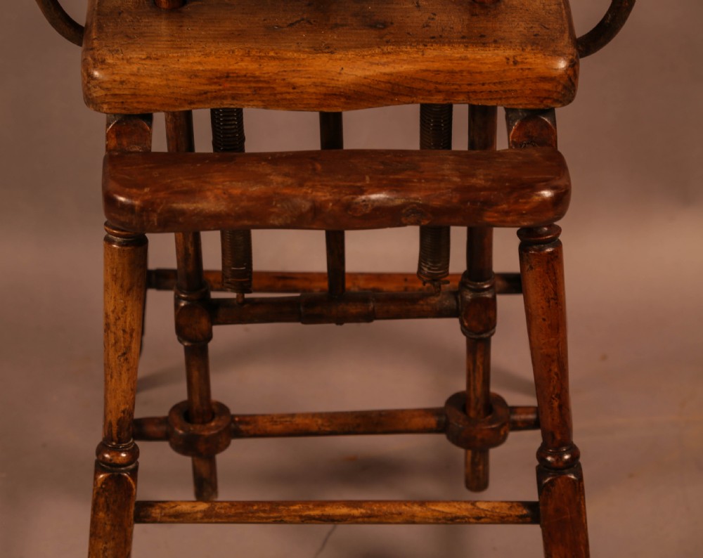 An antique Victorian yew wood child exercise chair featuring a hoop-back top seat, side metal handles, coiled steel springs, and turned legs. View VII