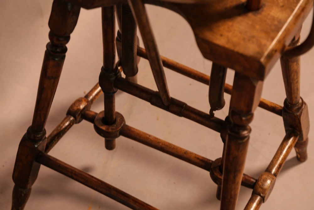 An antique Victorian yew wood child exercise chair featuring a hoop-back top seat, side metal handles, coiled steel springs, and turned legs. View X