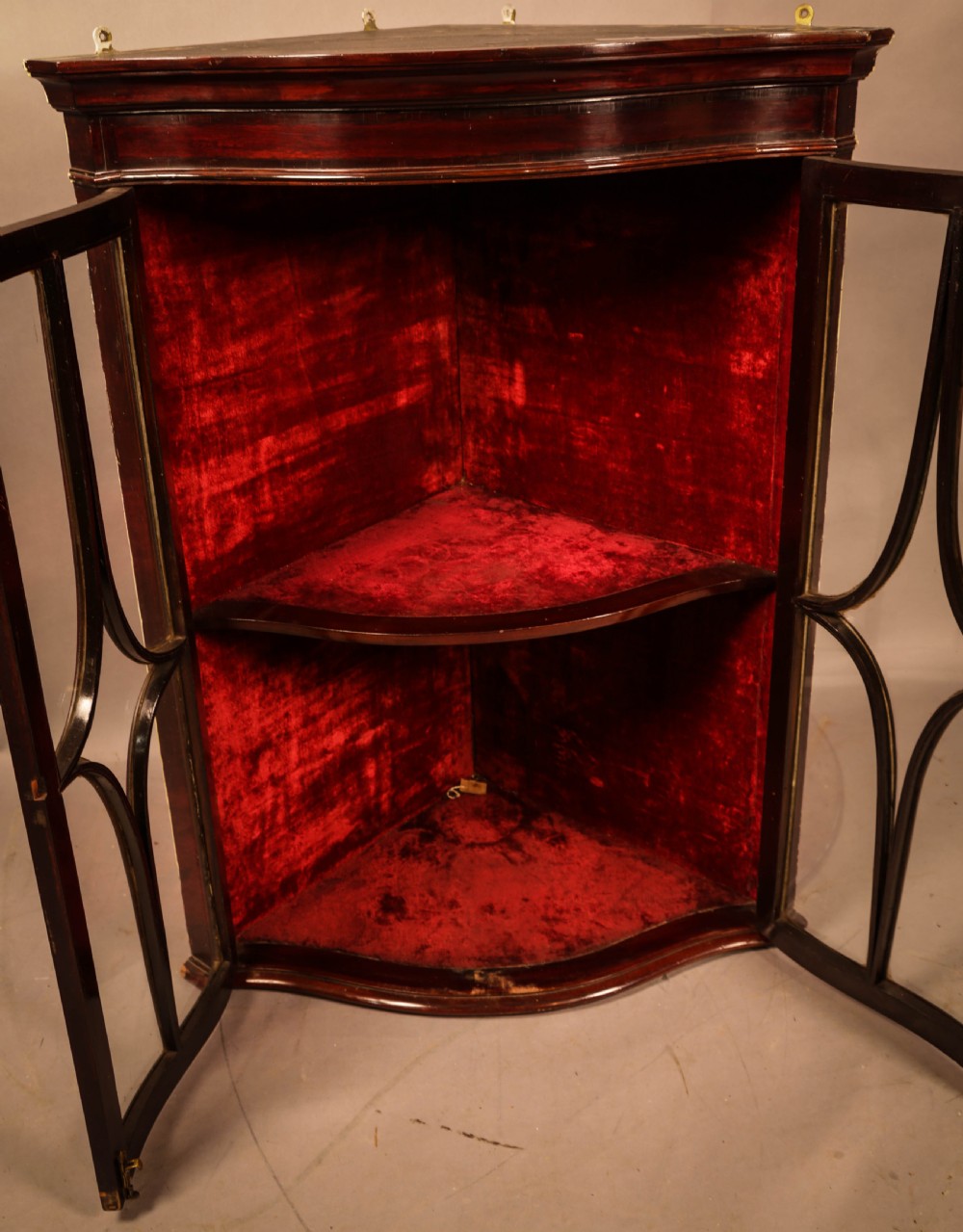 A dark mahogany wall-hanging corner cupboard featuring glazed double doors with serpentine curved fronts and decorative astragal glazing bars. View II