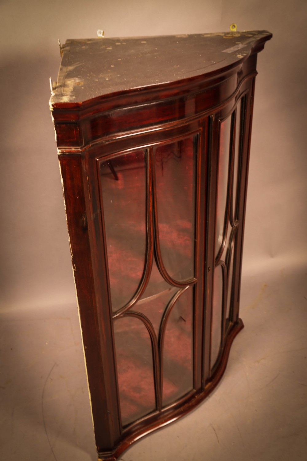 A dark mahogany wall-hanging corner cupboard featuring glazed double doors with serpentine curved fronts and decorative astragal glazing bars. View V