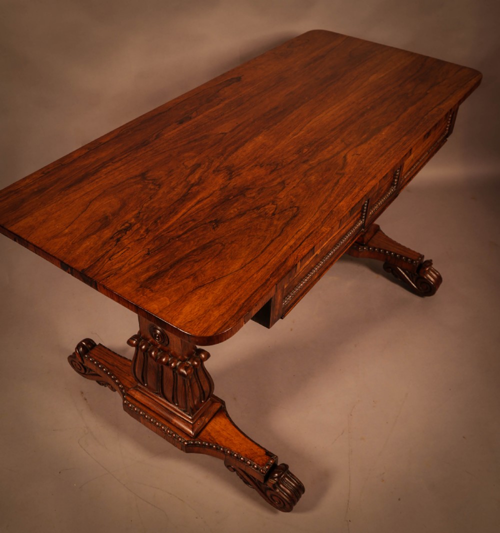 A William IV rosewood library table featuring a rectangular top with rounded corners, frieze drawers, a turned central stretcher, and carved pedestal legs. View III