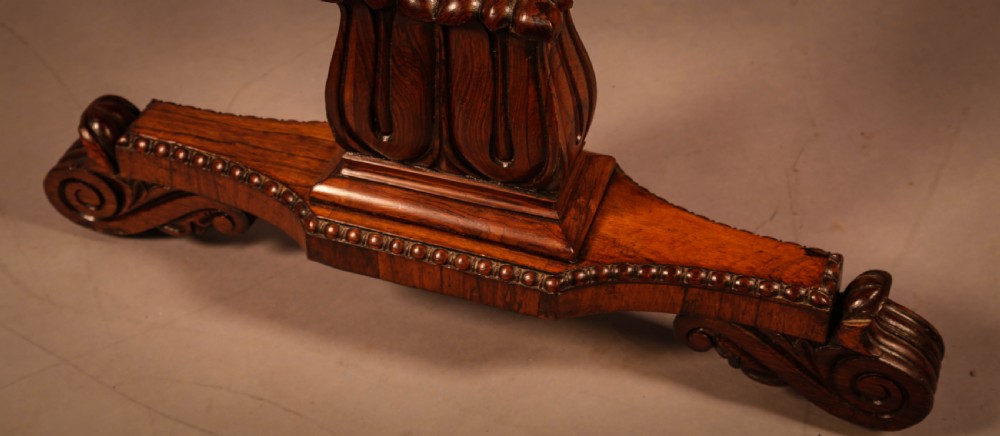 A William IV rosewood library table featuring a rectangular top with rounded corners, frieze drawers, a turned central stretcher, and carved pedestal legs. View V
