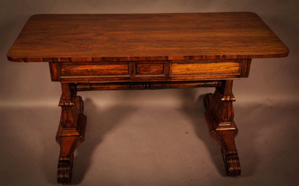 A William IV rosewood library table featuring a rectangular top with rounded corners, frieze drawers, a turned central stretcher, and carved pedestal legs. View VII