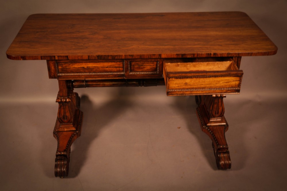 A William IV rosewood library table featuring a rectangular top with rounded corners, frieze drawers, a turned central stretcher, and carved pedestal legs. View VIII