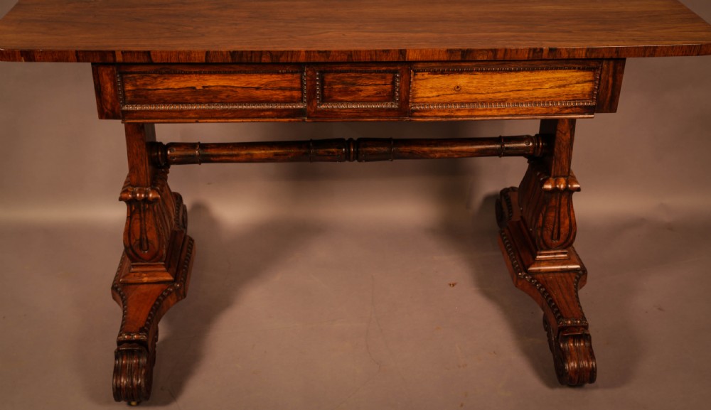 A William IV rosewood library table featuring a rectangular top with rounded corners, frieze drawers, a turned central stretcher, and carved pedestal legs. View IX