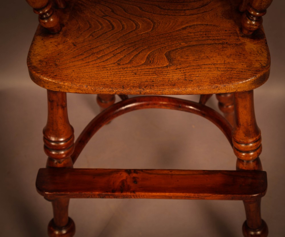 A yew wood Windsor childs high chair with a pierced splat back, turned legs, footrest, and safety bar. View IV