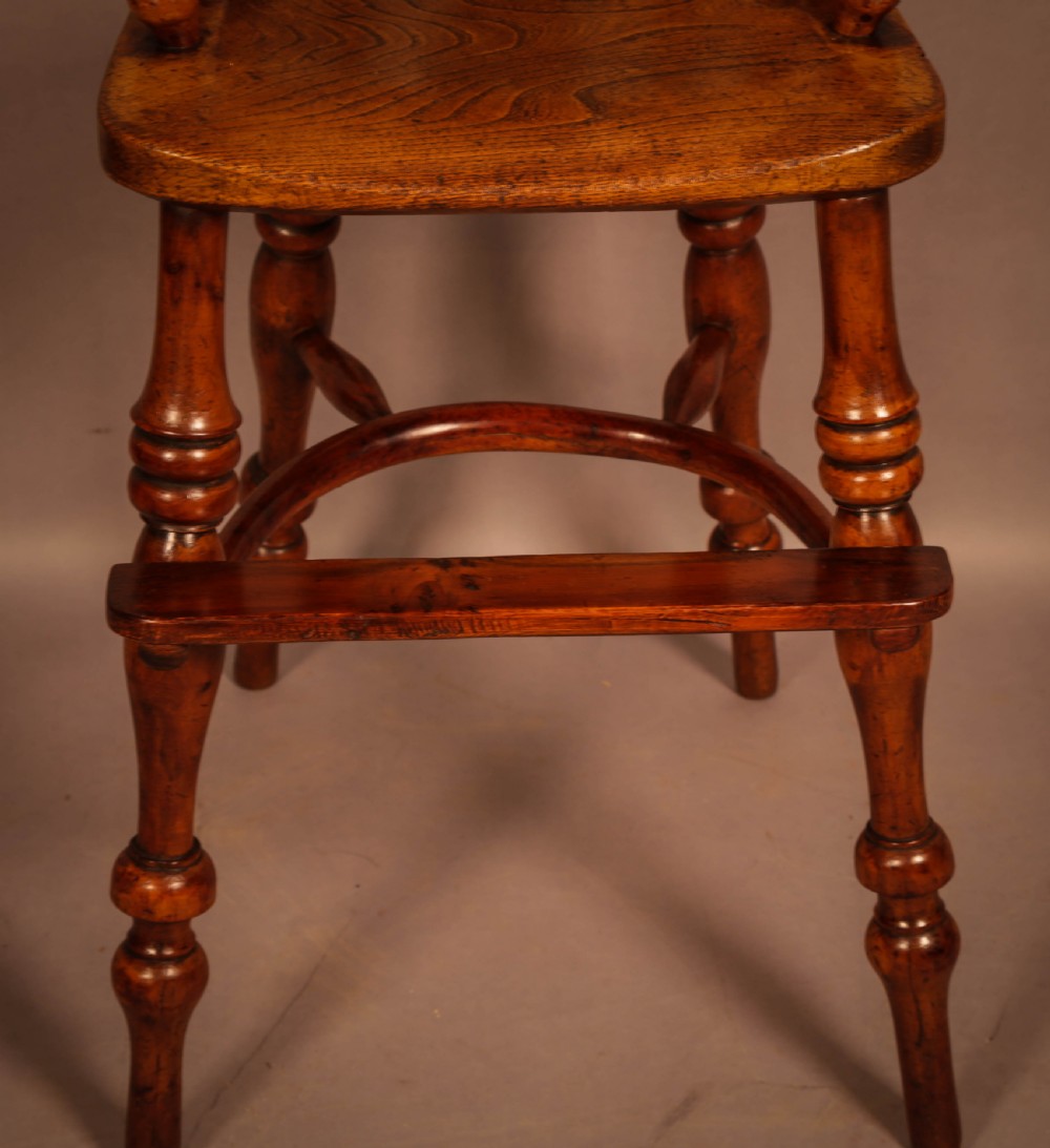 A yew wood Windsor childs high chair with a pierced splat back, turned legs, footrest, and safety bar. View V